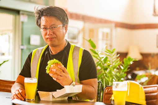 Workman wearing high visibility clothes eating a healthy hamburger after work